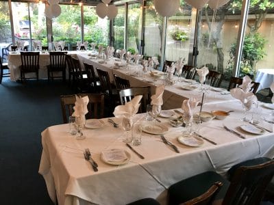 Elegant Sea Shore Restaurant patio with tables set for dining, featuring white tablecloths, napkins, and glassware.