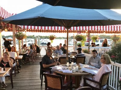 Outdoor dining at Sea Shore Restaurant patio with sunset views, vibrant flowers, and waterfront ambiance.