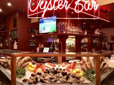 Sea Shore Restaurant Oyster Bar interior with fresh seafood display, neon sign, and sports on TV.