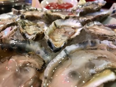 Fresh oysters on ice with cocktail sauce, seafood platter, close-up shot, gourmet dining experience, raw shellfish.